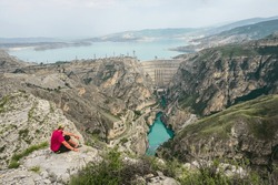 Hiker on a cliff overlooking the Chirkey dam and the Sulak canyon in Dagestan