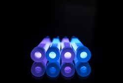 Blue and purple glowsticks in a row on a reflective surface