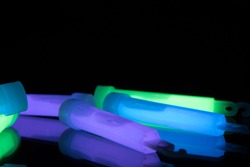 Purple, green and blue glowsticks on a reflective surface