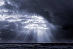 Dramatic seascape with sunbeams through clouds