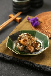 Japanese cuisine，Conch slices on a green plate on a straw mat