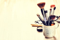 Various makeup brushes on light background with copyspace