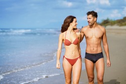 Young couple of beautiful athletic bodies walking together on the beach enjoying their holiday at sea