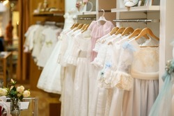 Display rack with first communion dresses for girls in a luxury children's clothing shop.