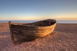 An old boat on Brighton beach by sunset