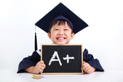Portrait of excited graduate little Asian boy student wearing graduation gown with hat holding a chalk board with the A+ sign, isolated on white background. Kid educational concept.