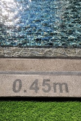 Pool depth warning sign on swimming poll side. Showing swimming pool depth of 0.45 meter. Selective focus image.