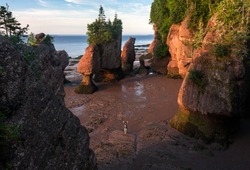 A woman waves from the beach, at the Hopewell Rock National park in New Brunswick, Canada. Taken at sunrise.