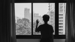 Someone standing by window with raindrops on a rainy day,Lonely silhouette in a window,black and white