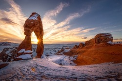 Beautiful sunset time at popular landmark Delicate Arch with snow in the winter season, Arches National Park, Moab, Utah.