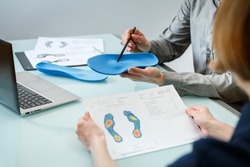 Doctor consulting patient on custom orthotic insoles in a clinic for a personalised custom fit. Feet recreation medicine concept