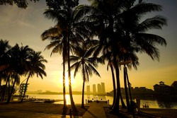 Beautiful twilight or sunrise scenery with reflection of jetty with coconut tree as a foreground of Pullman lakeside Putrajaya city, Malaysia.
