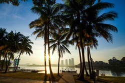 Beautiful twilight or sunrise scenery with reflection of jetty with coconut tree as a foreground of Pullman lakeside Putrajaya city, Malaysia.