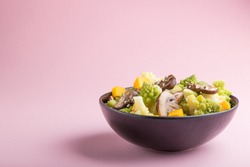 Vegetarian salad from romanesco cabbage, champignons, cranberry, avocado and pumpkin on a pastel pink background. side view, copy space.