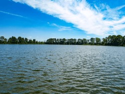 Lake Zegrzyński lagoon photographed during the day, against the background of a beautiful blue sky with white clouds, trees in the distance