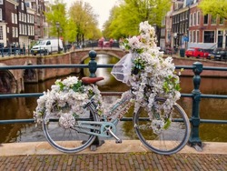 Old vintage bicycle decorated with white flowers on small bridge in old part of Amsterdam