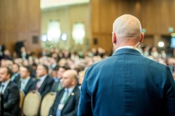 Security guard standing in the business meeting. Mature security guard listening to earpiece against Crowd. Secret service agent listening to his earpiece, side.