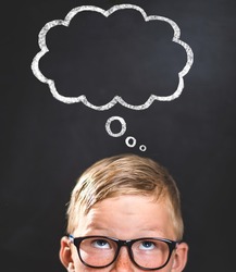 Kid thinking of future plans. School boy in glasses with graphic cloud for your text above in blackboard. Think, dream, genius concept. Nerd child go back to school.