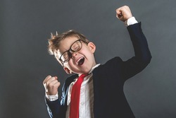 Portrait of little kid businessman celebrating victory. Say yes. Child winner excited and raising up hands in triumph. Achieving success grinning from delight. Caucasian female student boy