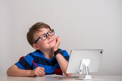 Child boy in glasses think and dream. Kid of primary school reading book. Online remote computer education. Child having computer video conference chat during quarantine and coronavirus outbreak