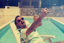 Young man on the swimming pool using cellphone.
