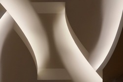 Close-up photo of glowing ceiling structure. Abstract architecture fragment. Modern interior design with curved elements. Geometric composition of curves and surfaces in gray halftones.