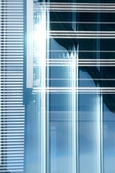 Window with blinds. Industrial or office building. Close-up of modern architecture. Hi-tech material structure of wall with glass and metal texture. Geometric pattern of rectangles and parallel lines.