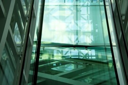 Smart double exposure photo of transparent lift shaft. Unreal sample of modern glass architecture with reflective walls. Minimalism / hi-tech interior design.