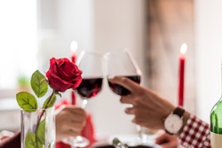 couple having a romantic dinner and toasting with cups of red wine.