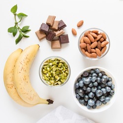 Healthy snacks: bananas, pumpkin seeds, vegan raw chocolate, almonds, blueberries and mint leaves. Vegan lifestyle. Natural sweets. Healthy diet. Top view