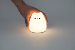 Cat shaped lamp on a dark background. Cute cat shaped silicone night lamp on a white background in a dark space.