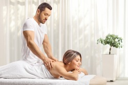 Masseur giving a back massage to a young woman at a beauty center