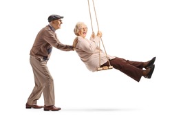 Full length shot of a senior man pushing a senior woman on a swing isolated on white background