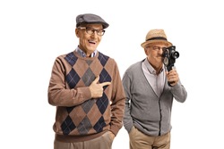 Elderly man laughing and pointing to another elderly man with 8mm camera isolated on white background