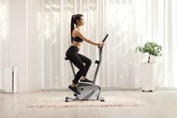Young woman riding a stationary bike at home