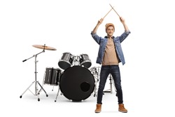 Young male musician standing and holding a pair of drumsticks isolated on white background
