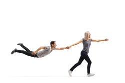 Young woman running and pulling a young man by the hand who is floating in air isolated on white background
