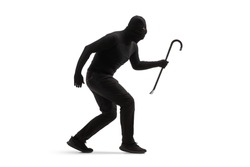 Full length shot of a burglar in black clothes with a balaclava and a crowbar walking slowly isolated on white background