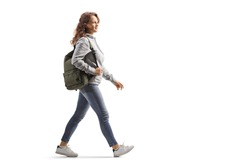 Full length profile shot of a female student in jeans with a backpack walking isolated on white background