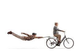 Elderly man riding a bicycle and other man flying behind isolated on white background