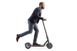 Full length profile shot of a young man in suit and jeans riding an electric scooter isolated on white background