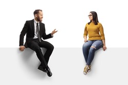 Businessman sitting on a panel and talking to a young casual female isolated on white background