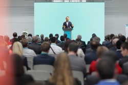 Man giving a speech on a podium in front of an audience in a conference hall 