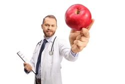 Young male doctor holding a clipboard and a red apple in front of camera isolated on white background 