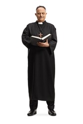Full length portrait of a mature priest standing and reading the bible isolated on white background