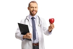 Young male doctor holding a clipboard and a red apple isolated on white background 