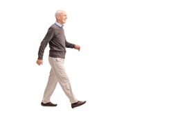 Full length profile shot of a casual senior man walking and smiling isolated on white background