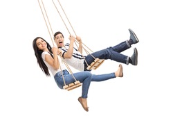 Young cheerful man and woman swinging on wooden swings isolated on white background