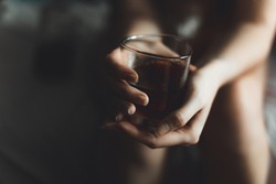woman holds glass with whiskey. alcohol cocktail in glass. woman's alcoholism, alcohol addict concept