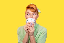 Girl with money. Closeup red head beautiful young woman pretty excited amazed greedy pinup girl green button shirt euro cash looking at currency retro vintage 50's hairstyle isolated yellow background